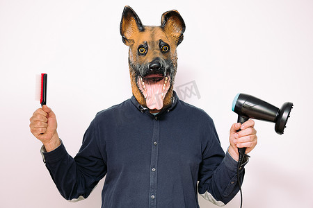 吹风机狗摄影照片_戴着狗面具的男人展示梳子和吹风机