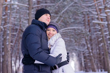 年轻美丽的夫妇在雪冬户外微笑