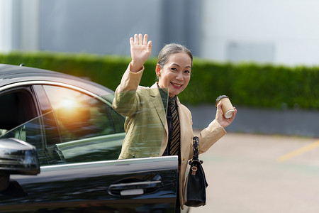 亚洲高级女商人的肖像在上班时走出豪华车。