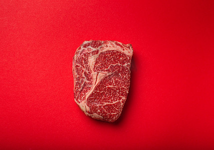 极简主义背景摄影照片_生肉牛肉优质切牛排肋眼从上面干净的红色背景，牛排概念横幅极简主义
