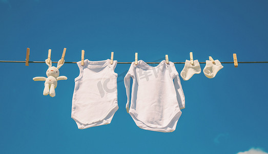 洗衣服男孩摄影照片_白色婴儿衣服在绳子上晾干。