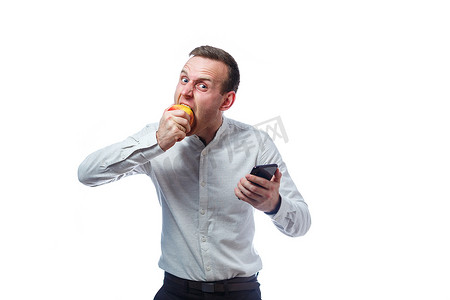 苹果手机黑色手机摄影照片_白种人男性商人拿着黑色手机，拿着红黄色苹果。