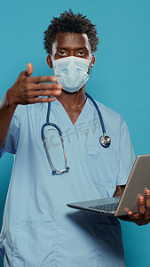 男护士戴着口罩，拿着笔记本电脑