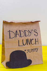 降解摄影照片_纸袋里装着美味爸爸的午餐，戴着帽子。