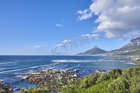 南非开普敦，平静的大海和绿色灌木丛的自然风光，地平线上有狮头山。