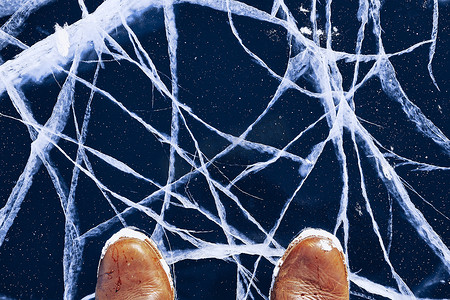 冰湖上摄影照片_贝加尔湖冰湖上穿着靴子的人脚。