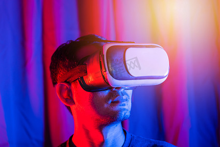 虚拟现实现实摄影照片_亚洲帅哥戴 VR 头盔在家里紫色和蓝色背景中情绪激动