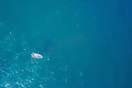 一艘停泊在蓝色大海中的白色小船的顶视图
