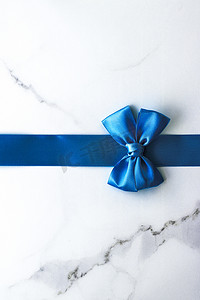 豪华大理石背景上的蓝色丝带和蝴蝶结、假日平底背景
