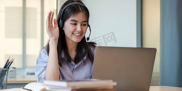 上学可爱摄影照片_由于科维德大流行，在家上学的白人可爱的年轻女学生通过远程会议向学校老师学习虚拟互联网在线课程。