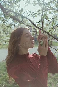 红衣女孩摄影照片_金发碧眼的红衣女孩呼吸着樱花的香味