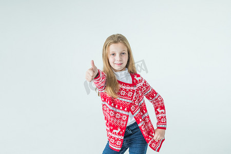 快乐的女孩跳舞的肖像保持举手在头戴圣诞毛衣隔离在白色背景。圣诞节和新年的概念。红色毛衣的积极女孩。圣诞节心情。