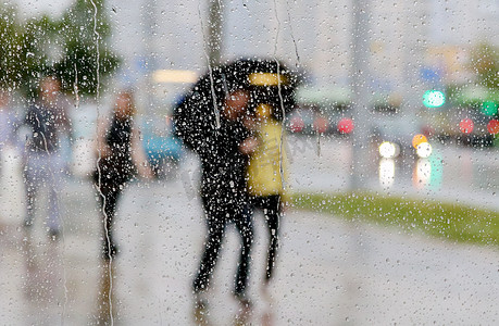 窗上的雨滴和打伞的人