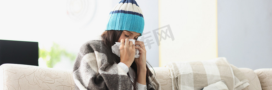为爱筑梦传递温暖摄影照片_戴着温暖帽子的病妇在家中用纸巾擤鼻涕