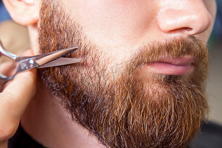 理发师用剪刀剃胡子的男人的特写