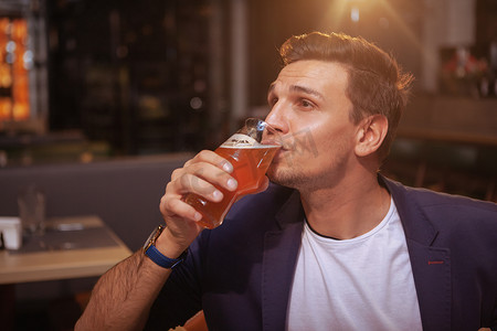 英俊的男人在酒吧喝啤酒