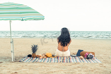 夏天穿着比基尼坐在海滩上的女人。