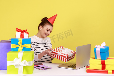 拿着礼品盒，看着笔记本电脑屏幕送礼物的女人，同时进行在线交流