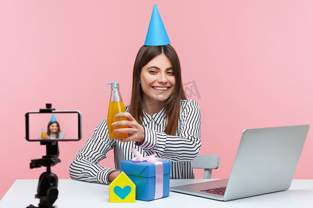 生日视频背景摄影照片_情绪化的年轻女性坐在粉红色背景的办公室里工作。