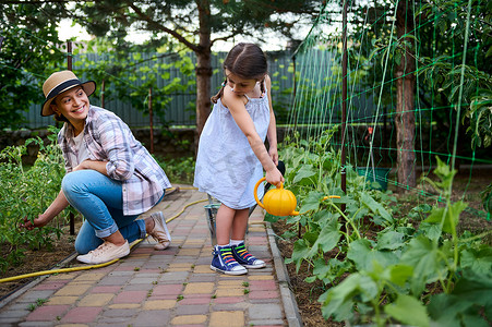 迷人的女人和她可爱的女儿 — 漂亮的女婴在家庭有机菜园里一起工作