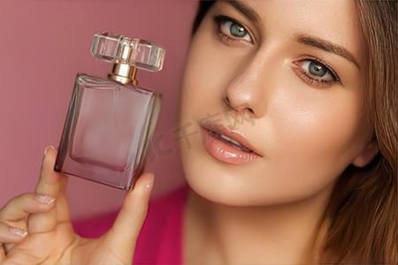 粉红色背景的香水、美容产品和化妆品模特脸部肖像，美丽的女人拿着带有花卉女性香味、时尚和化妆的香水瓶