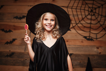 万圣节女巫概念 — 小女巫孩子带着万圣节甜蜜和糖果，带着欢快的微笑。