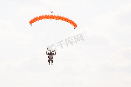 跳伞运动员，背景是蓝天，有一个降落伞的小天篷，特写。