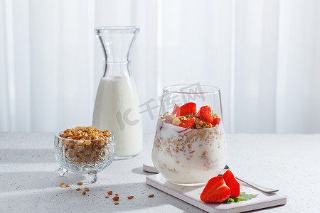 一杯健康酸奶，配有新鲜浆果和灰色背景的格兰诺拉麦片。健康早餐。