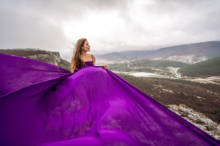 一名长发女子，身穿紫色飘逸长裙，布料飘逸，站在那里。