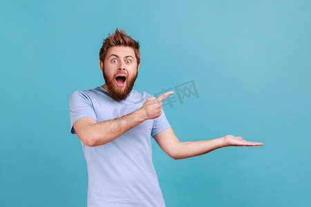 身穿蓝色 T 恤的男子在手掌上展示复制空间，显示商业文字或商品的空位。