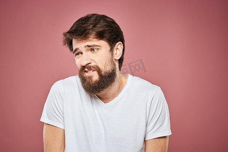 表情摄影照片_情绪化的男人白色T恤悲伤的面部表情粉红色背景