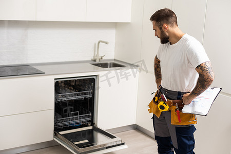 洗碗工具摄影照片_男人用工具修理洗碗机
