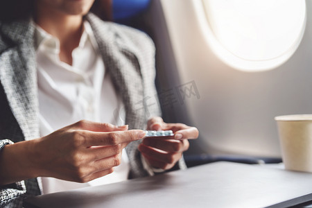 一位成功的亚洲女商人或企业家在商务舱的飞机上穿着正式的西装，在飞行期间服用晕车药