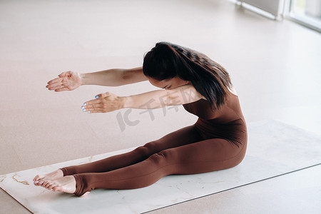 一位身穿棕色西装的女士在健身房里做瑜伽。