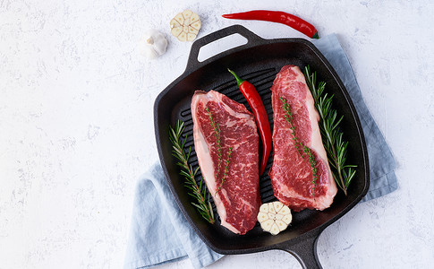 两块新鲜的生肉、牛肉片、大理石里脊肉放在铸铁大锅里。