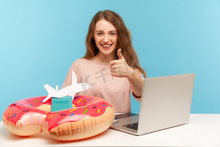 在蓝色背景上使用笔记本电脑的情感年轻女子。