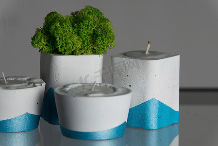 白色和蓝色混凝土烛台中的蜡烛和苔藓