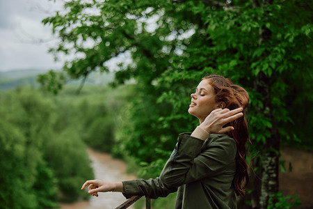 一位红发随风飘扬的美丽女子站在公园里，俯瞰山河