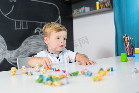 可爱的幼儿男孩在家里的桌子上玩玩具的肖像。