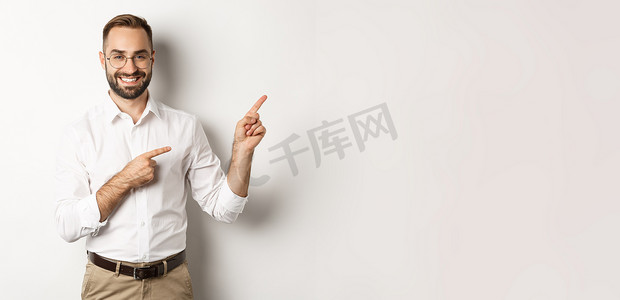 英俊的成功商人用手指指着右边，以高兴的脸、白色背景展示广告