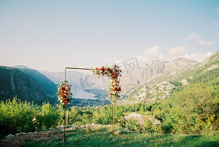 矩形金属婚礼拱门矗立在山上，俯瞰群山和海湾
