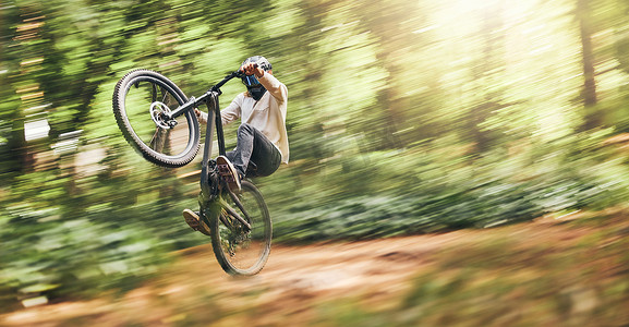 免费建党节摄影照片_山地自行车男子的运动模糊、动作跳跃和自行车速度冒险、自由和树林中的快速比赛。