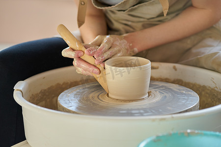 女人在轮子上制作陶瓷陶器，手特写，专注于陶艺家，手掌上有陶器