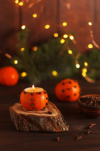 橘色装饰摄影照片_桌子上的木架上放着一个橘子烛台，上面装饰着冷杉树枝和圣诞灯。