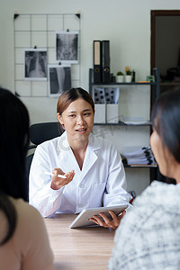 一位医生拿着平板电脑工作并与前来治疗的患者交谈，为客户提供健康问题建议的肖像