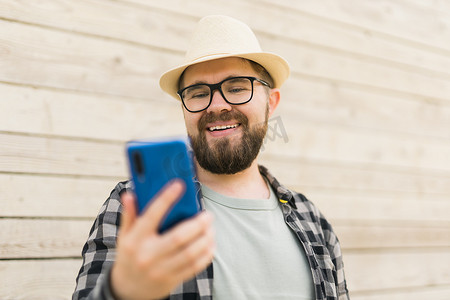 夏季城市突破木墙时，微笑的男性游客使用智能手机 — 技术和社交媒体应用概念