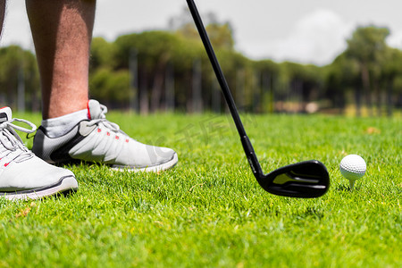 高尔夫上杆摄影照片_男子站在高尔夫球铁杆上，准备在高尔夫球场的绿草上击球