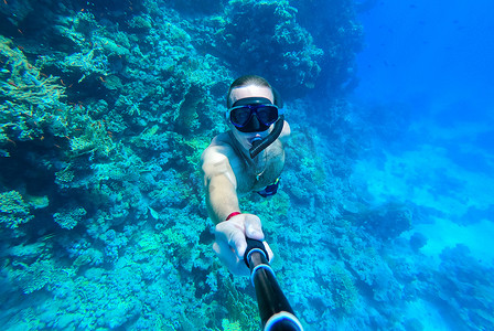 一名戴着面罩和通气管的男子潜入红海蓝色的海水中并拍摄自己的照片