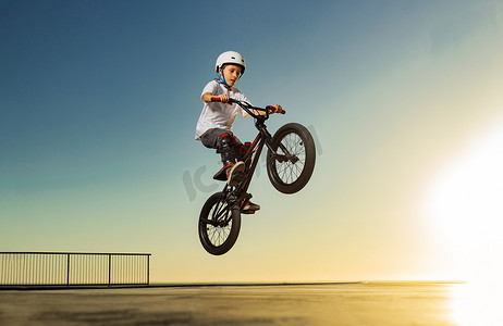 一名青少年 BMX 赛车手在滑板公园的泵道上表演特技。