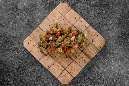 炸贻贝配辣椒、大蒜、芝麻、香草，在​​灰色背景的方形木板上。